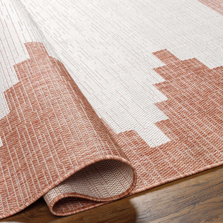 Close-up of a pink geometric patterned rug on a wooden floor.

Djugun Peach Fuzz Indoor & Outdoor Area Rug
