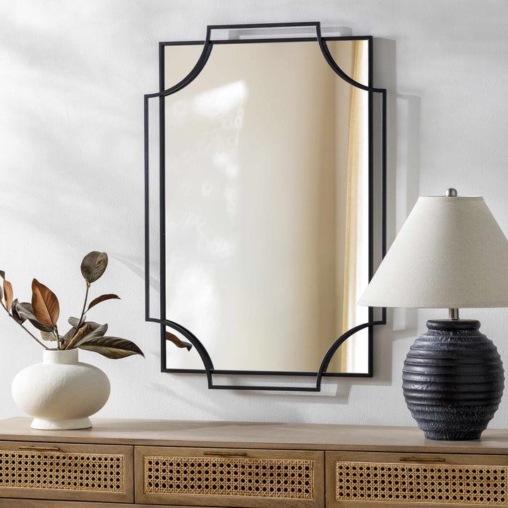 Decorative mirror with black frame on a wall above a wooden console table with a lamp and plant.

Golasecca Black Frame Mirror