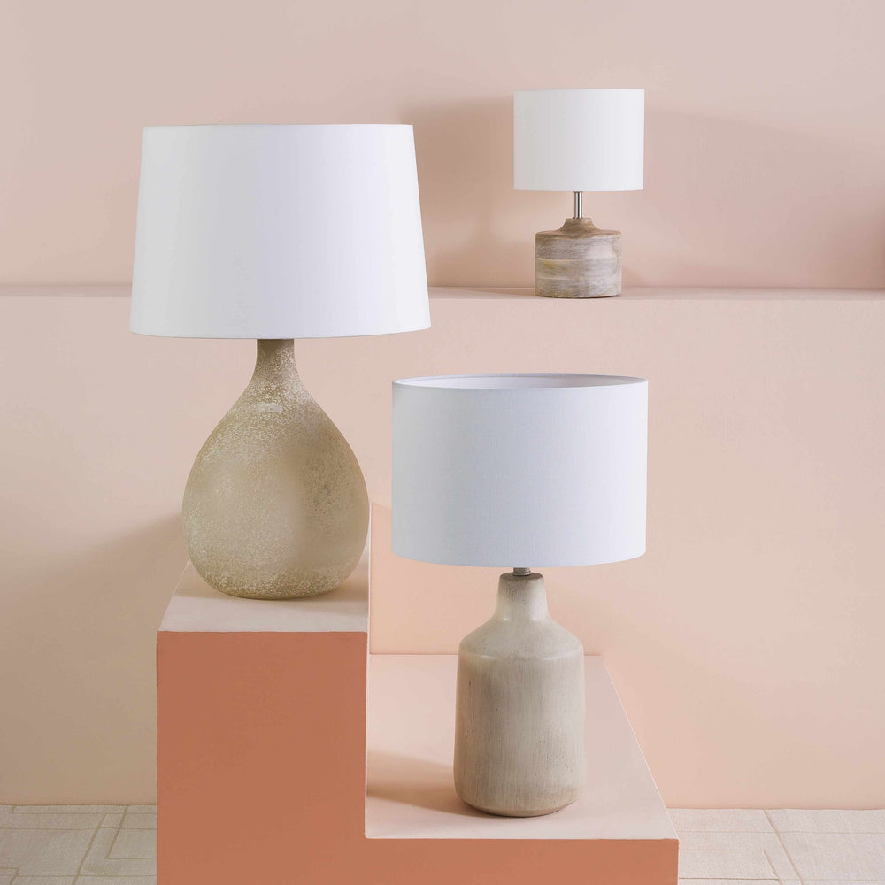 Three table lamps with ceramic bases and white lampshades on a pink background

Quezon Beige Resin Table Lamp