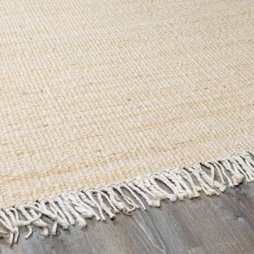 Beige woven rug with fringe on a wooden floor

Iantha Jute Rug