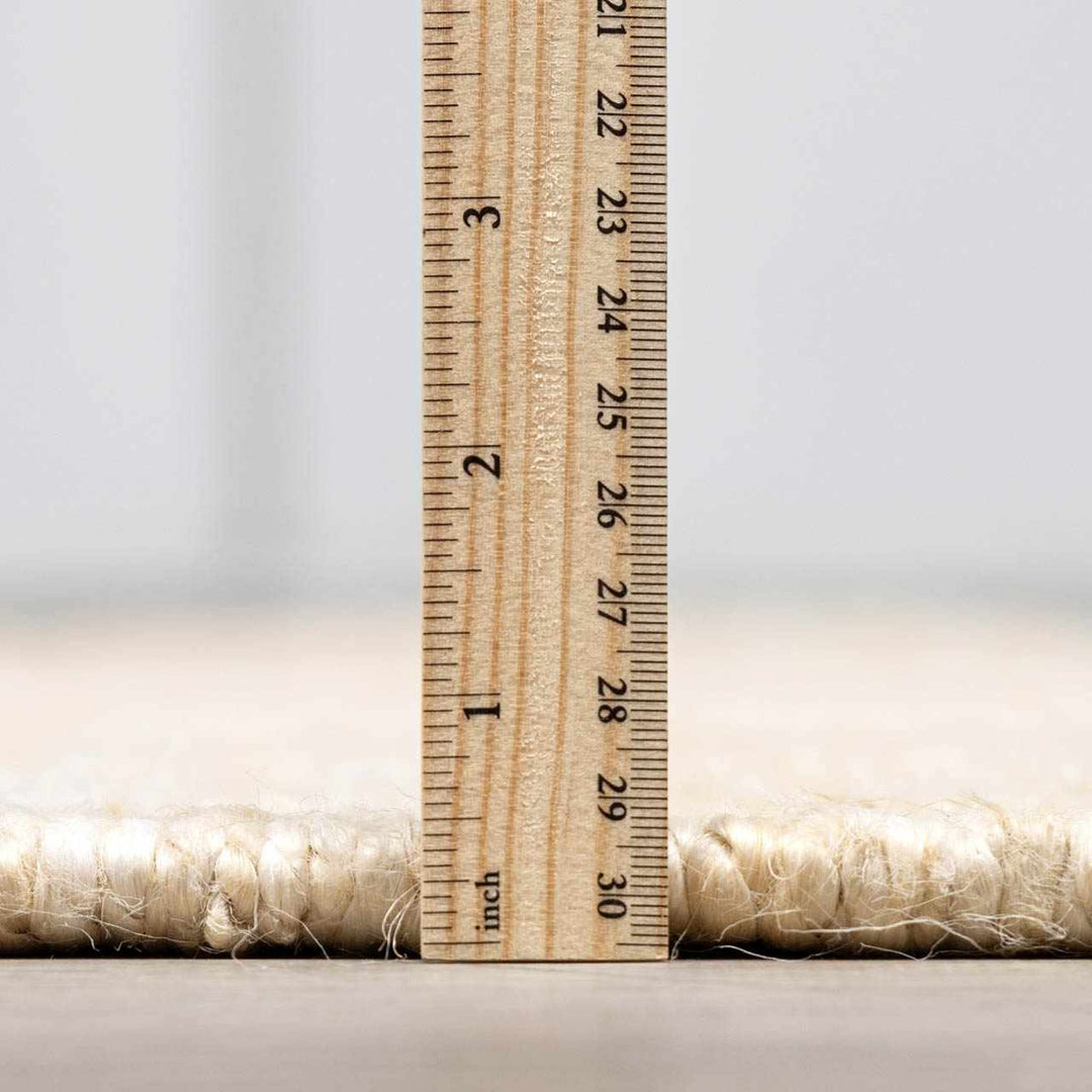 Wooden ruler next to a roll of fabric on a light background

Iantha Jute Rug