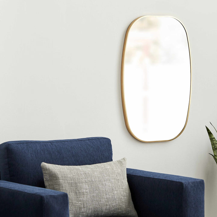 Gold-framed mirror on a white wall above a blue armchair with a gray pillow.

Kopparberg Gold Frame Round Mirror