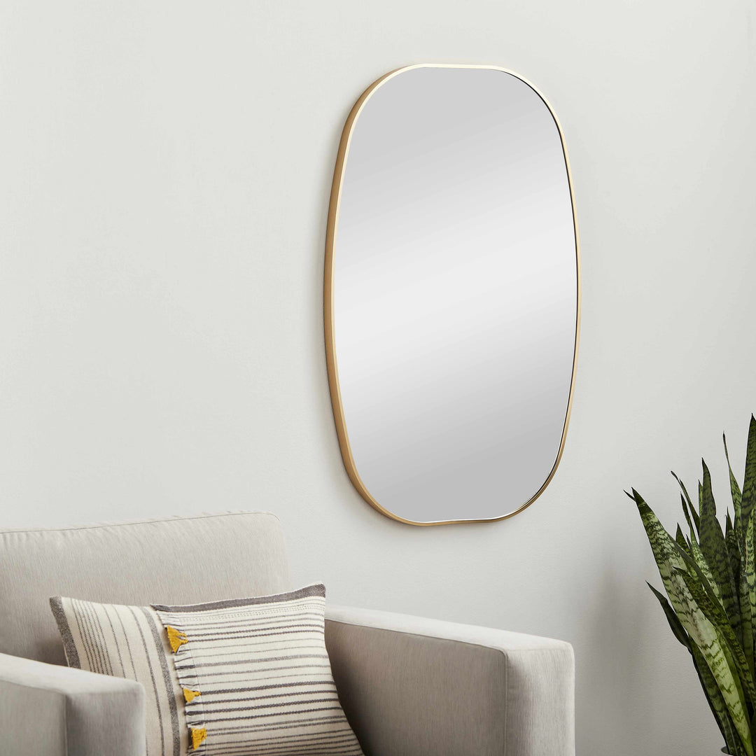Wall mirror with gold frame on a light gray wall above a sofa with cushions.

Kopparberg Gold Frame Round Mirror