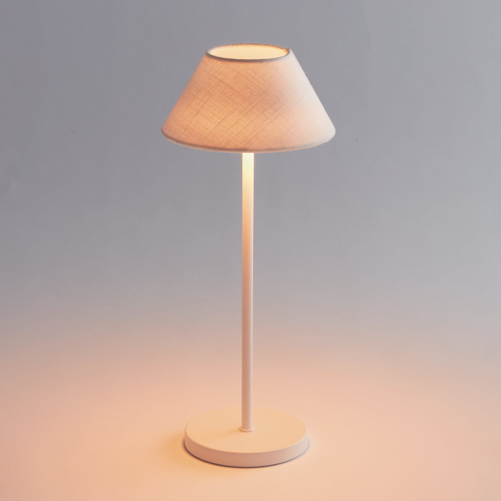 A white cordless LED lamp with a linen shade and a round white base, designed for indoor use.

ALLUNA CORDLESS LED LAMP 14" - White with Linen Shade
