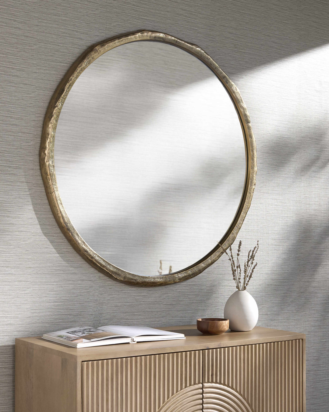 Round mirror with gold frame on a textured wall above a wooden console table.

Vallelado Gold Accent Mirror
