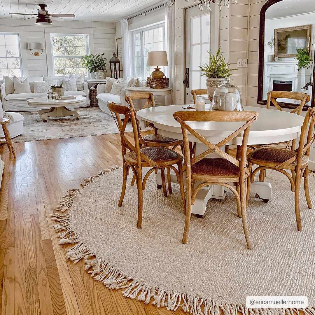 Dining area with wooden chairs and table on a beige rug, living room in the background

Iantha Jute Rug