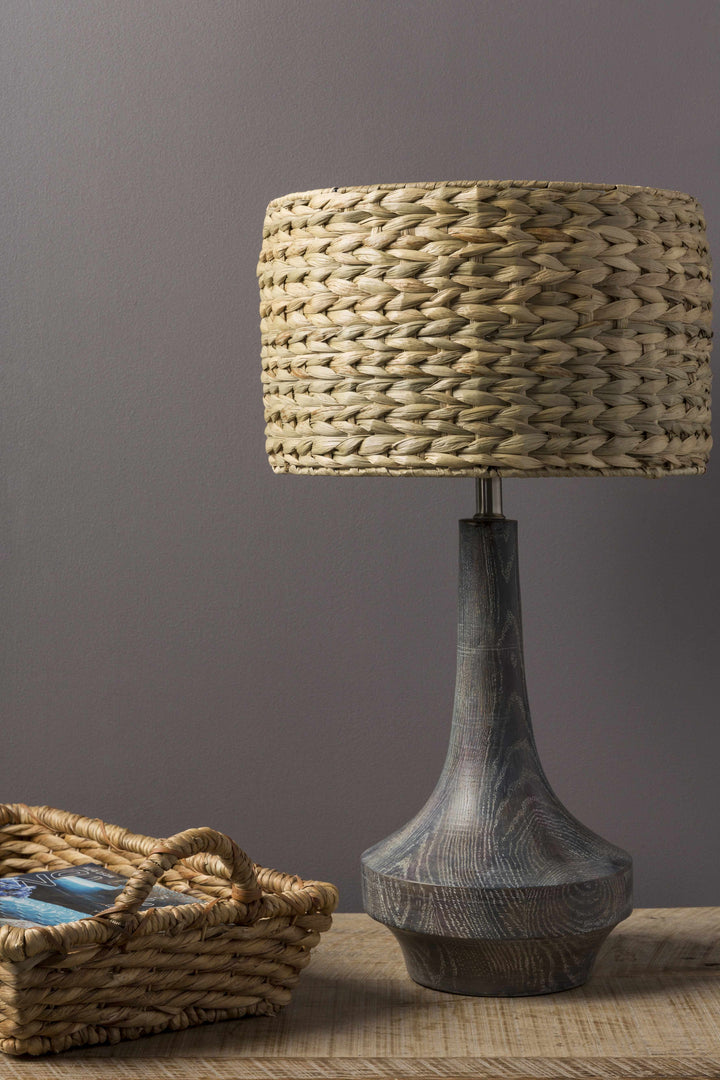 Table lamp with woven shade and textured base on a wooden surface against a gray background

Kabankalan Seagrass Resin Table Lamp