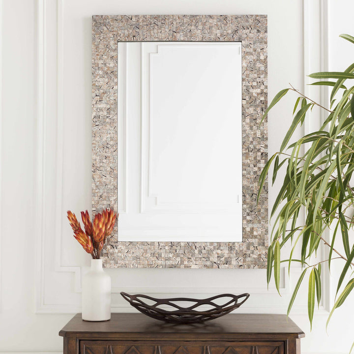 Decorative mirror with mosaic frame on a wall above a wooden console table with a vase and bowl.

Nicolet Marble Mirror