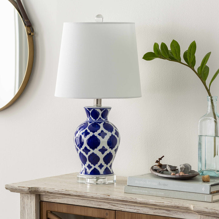Decorative lamp with blue pattern on a wooden table with books and a plant.

Pangian White & Blue Patterned Ceramic Table Lamp